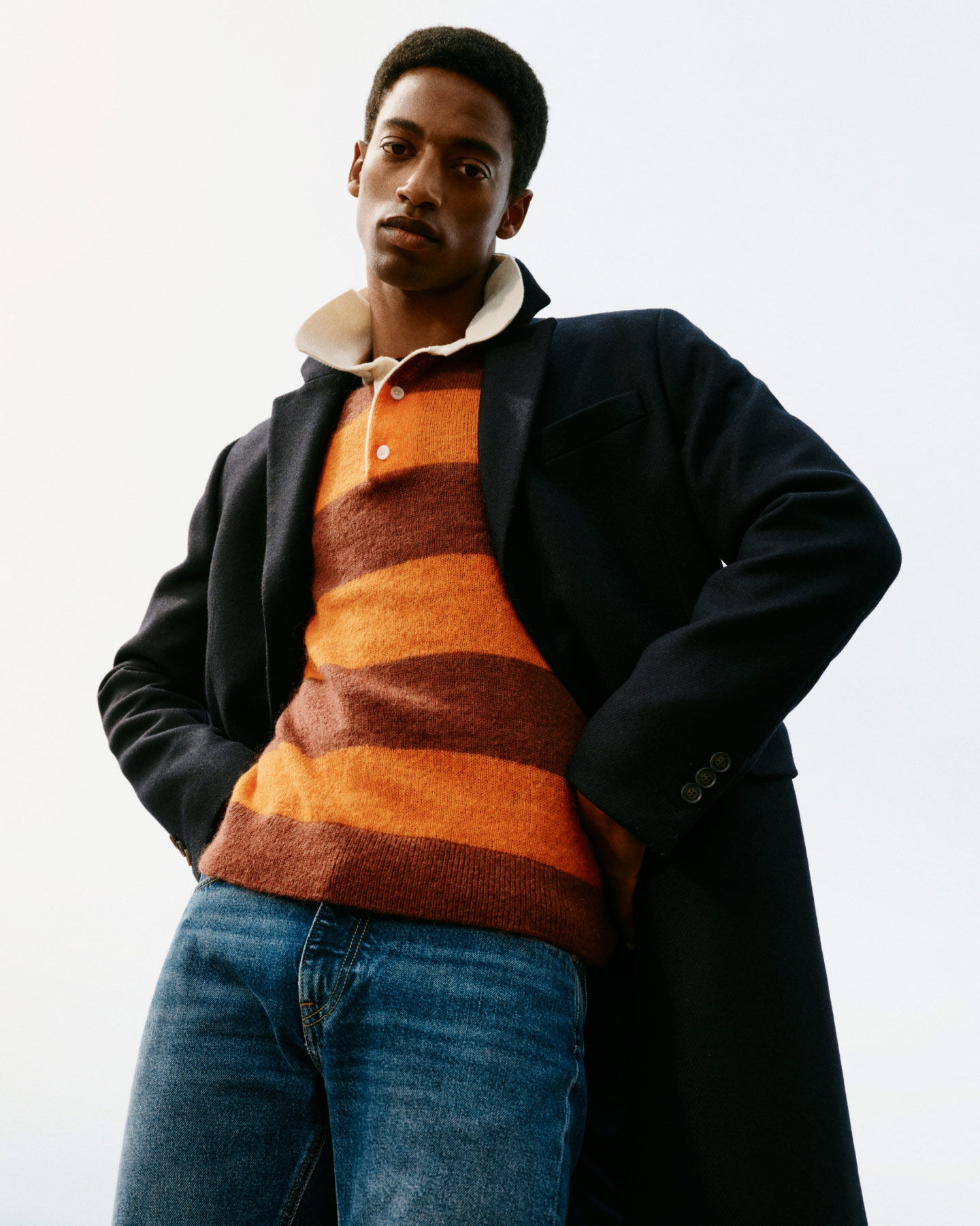 Man wearing Classic Wool Coat in evening blue, Barstriped rugger in color golden orange and Hayes Slim Fit Authentic Jeans.